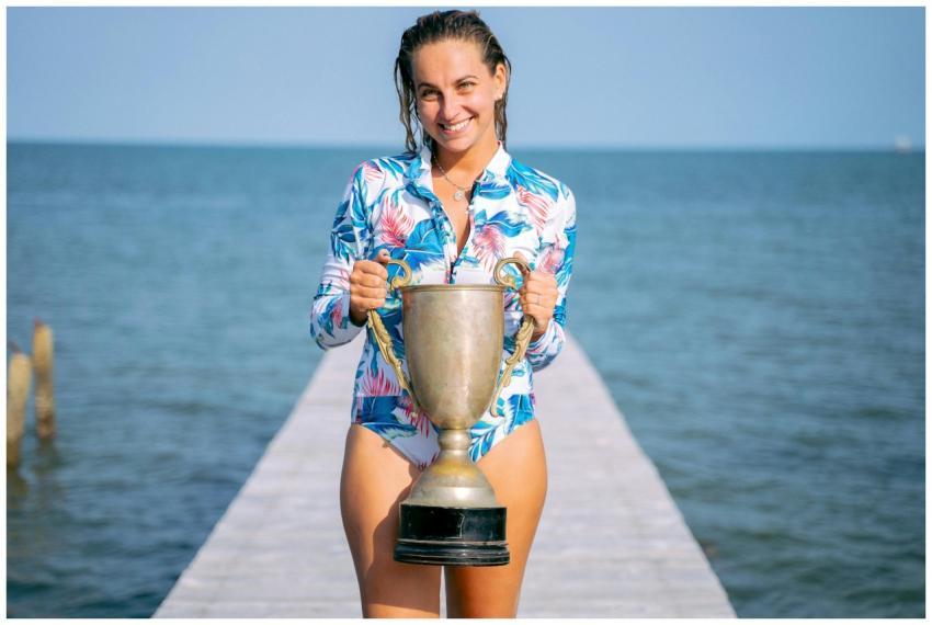A joyful woman in a floral swimsuit holding a trop