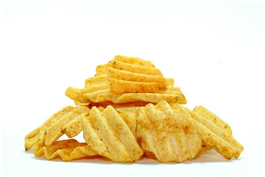 A close-up of crispy wavy potato chips stacked aga