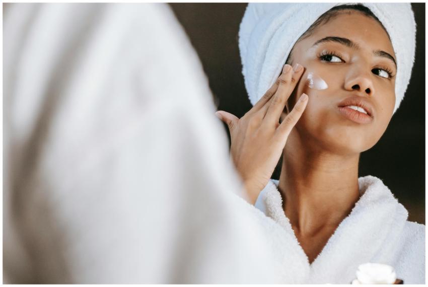 Woman in a bathrobe practices her skincare routine