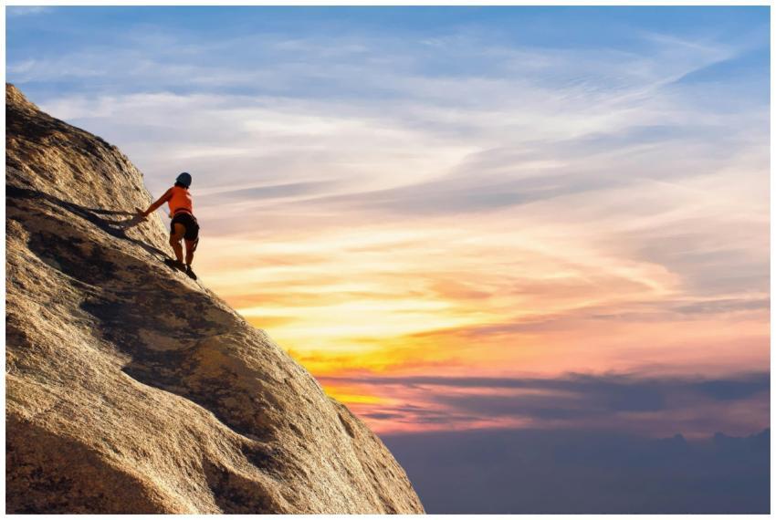 Climber conquers rock face at sunset, embracing th