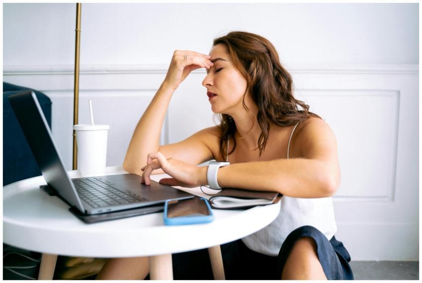 Woman experiencing work fatigue with laptop at a t