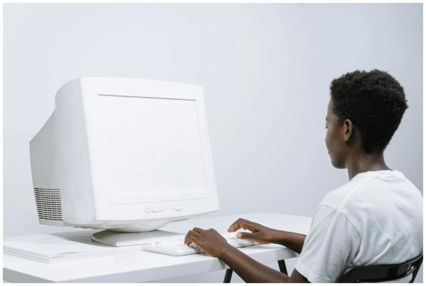 An adult man typing on a white CRT monitor in a mi