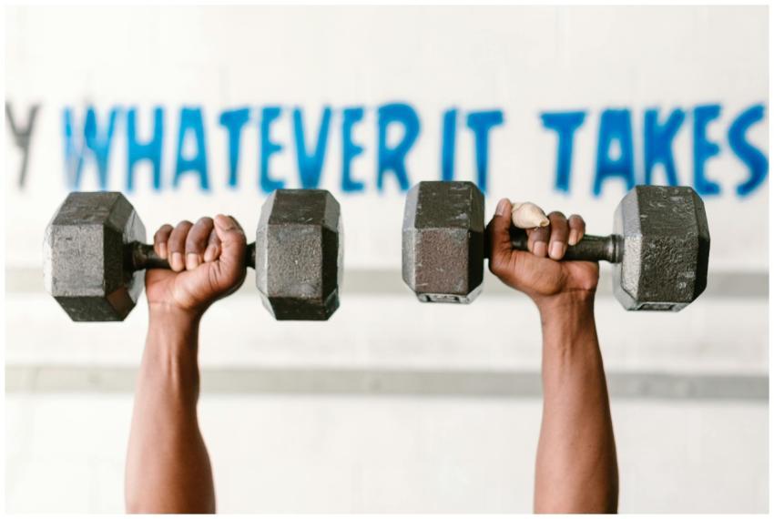 Hands holding dumbbells against motivational text