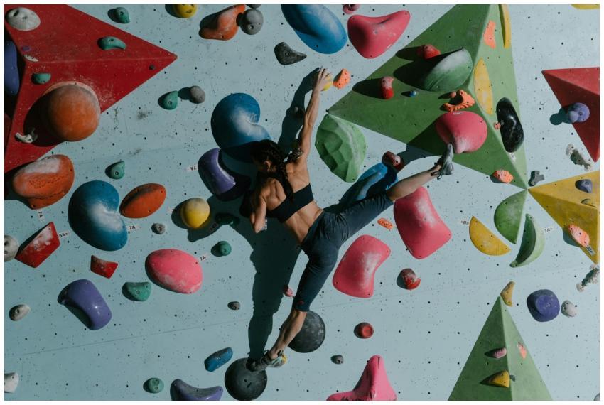Focused woman rock climbing indoors on a colorful