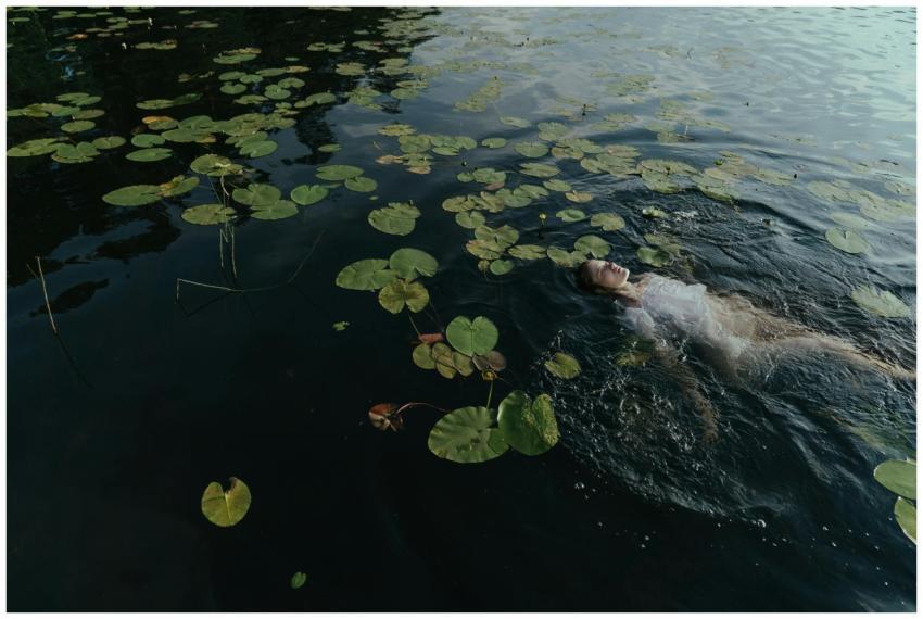 A woman peacefully floating in a lake surrounded b