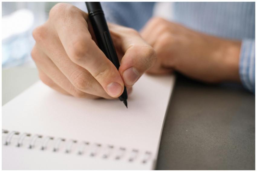 Detailed image of a hand writing with a pen on a s