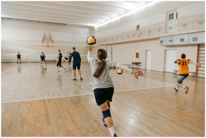 Coed volleyball team practicing indoors, focusing