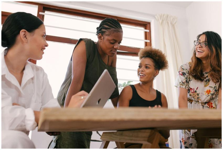 Four women in an office setting engaged in a livel