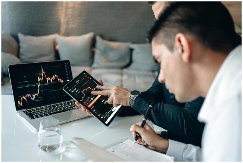 Two businessmen analyzing stock charts on a laptop