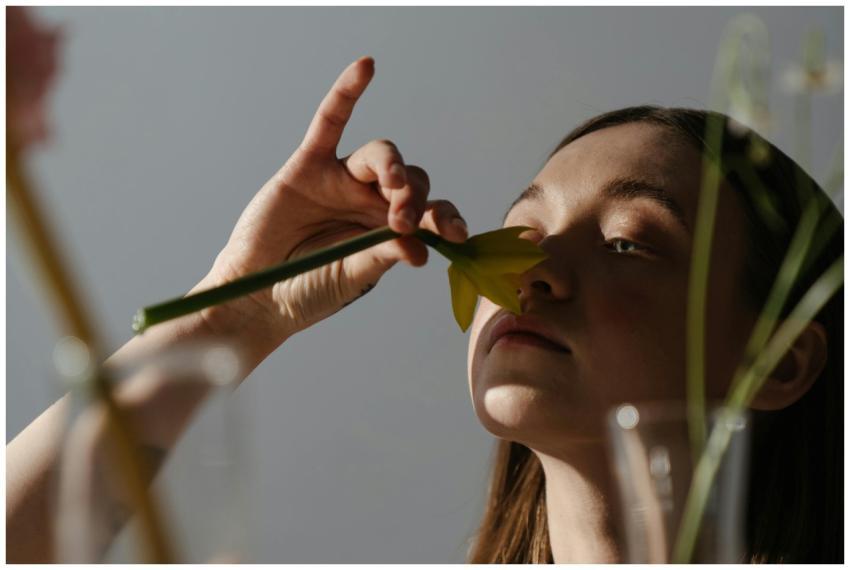 Adult woman gently smelling a daffodil flower indo
