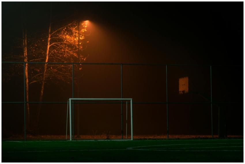 A dimly lit soccer field at night with an atmosphe