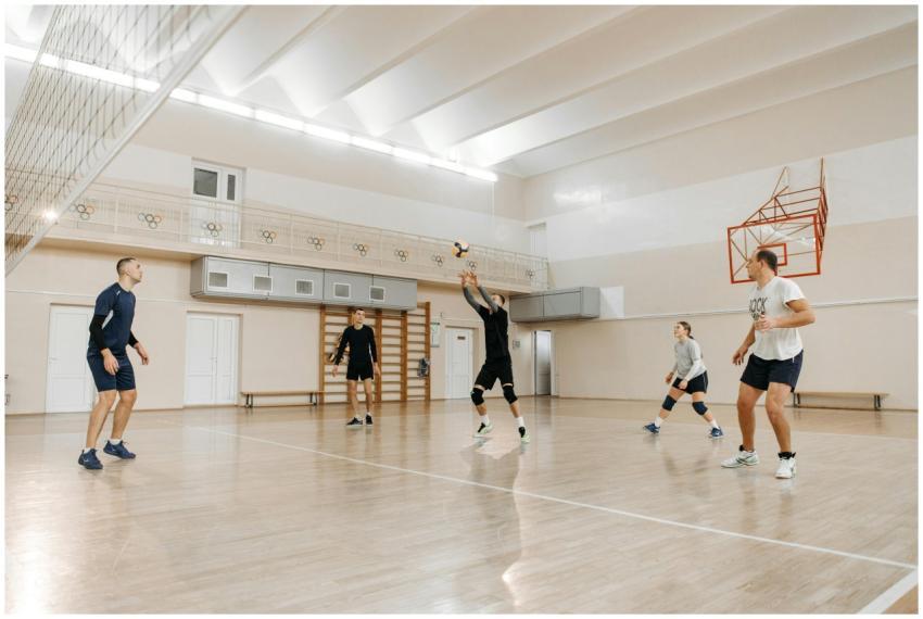 Group of athletes playing volleyball indoors, show