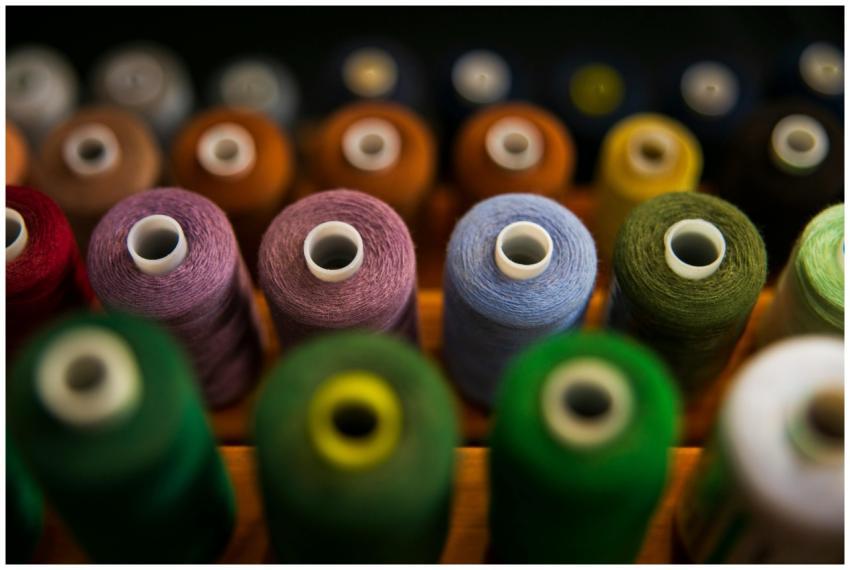Colorful sewing thread spools arranged in rows, sh