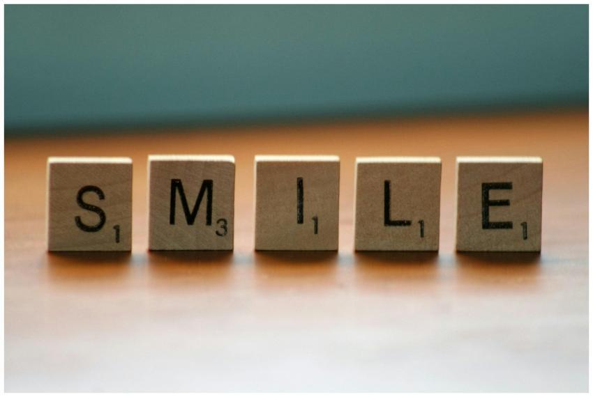 Scrabble tiles spelling 'Smile' on a wooden surfac