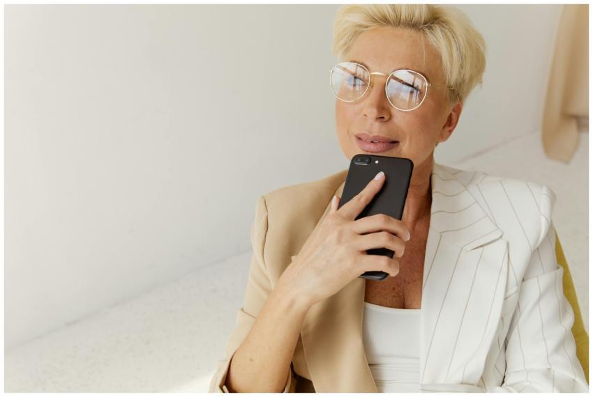 Confident businesswoman in glasses holding smartph