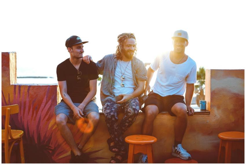 Three friends relax on a Tel Aviv rooftop, soaking