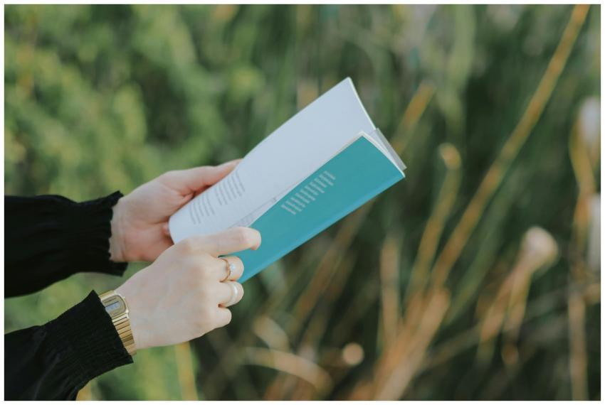 Person in black sleeves holding and reading a book
