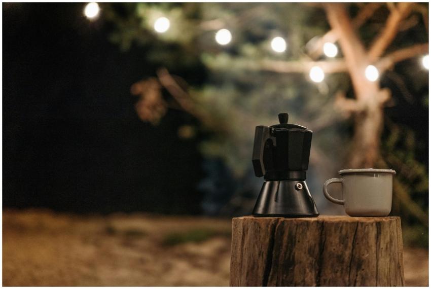 A ceramic cup and moka pot on a tree stump with st
