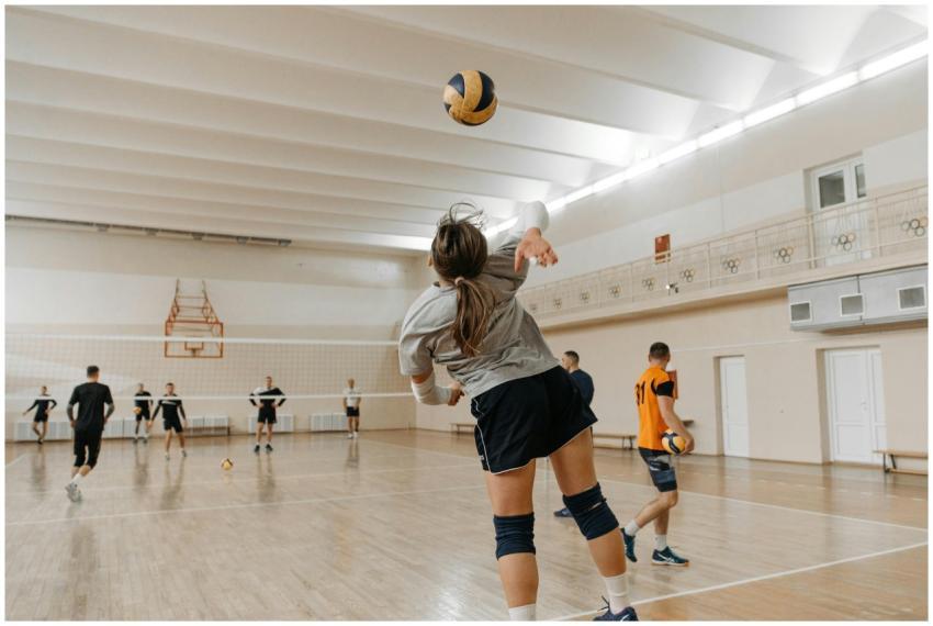 Team practicing volleyball indoors, focusing on a