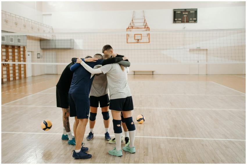 Team of young adults huddling on an indoor volleyb
