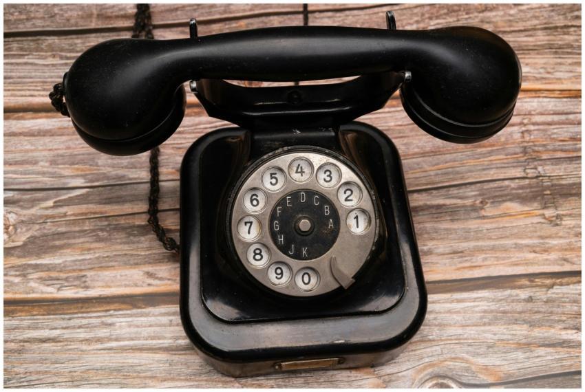 Classic black rotary telephone with dial on wooden