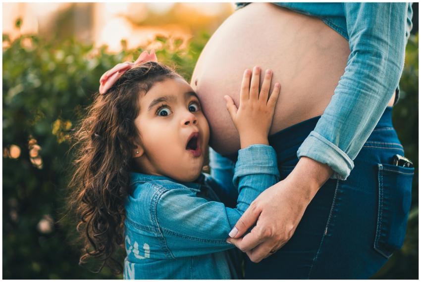 A young girl joyfully embraces her pregnant mother