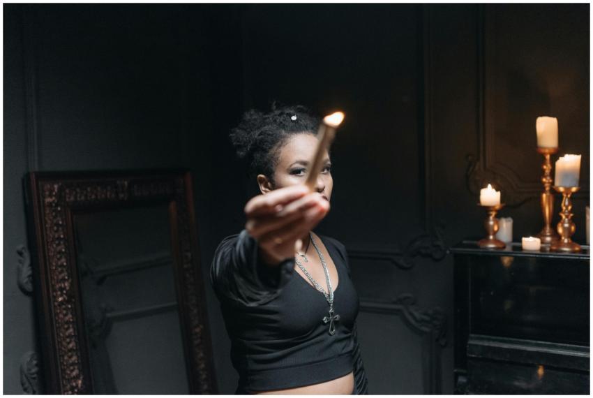 A woman stands in a dark room, holding a burning c