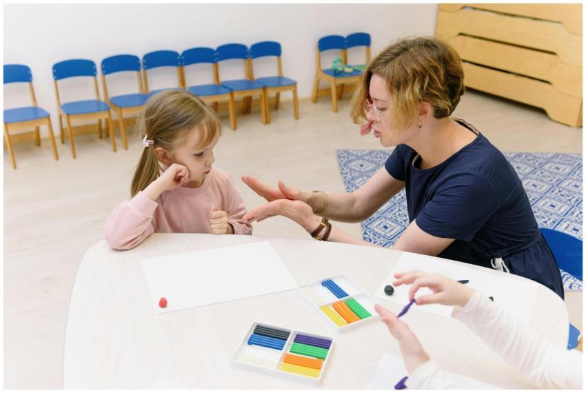 A teacher helps a child with a clay molding activi