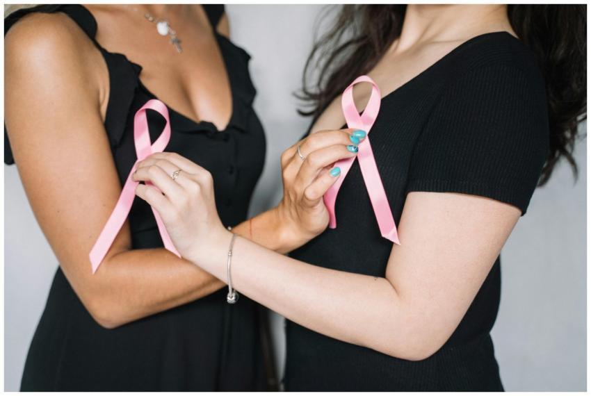 Close-up of two women holding pink ribbons symboli