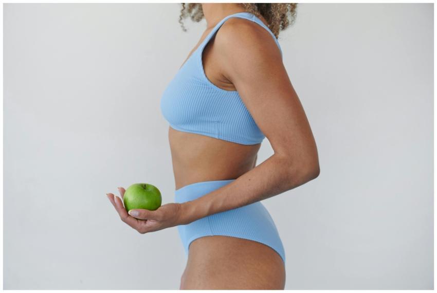 A woman in blue activewear holding a fresh green a
