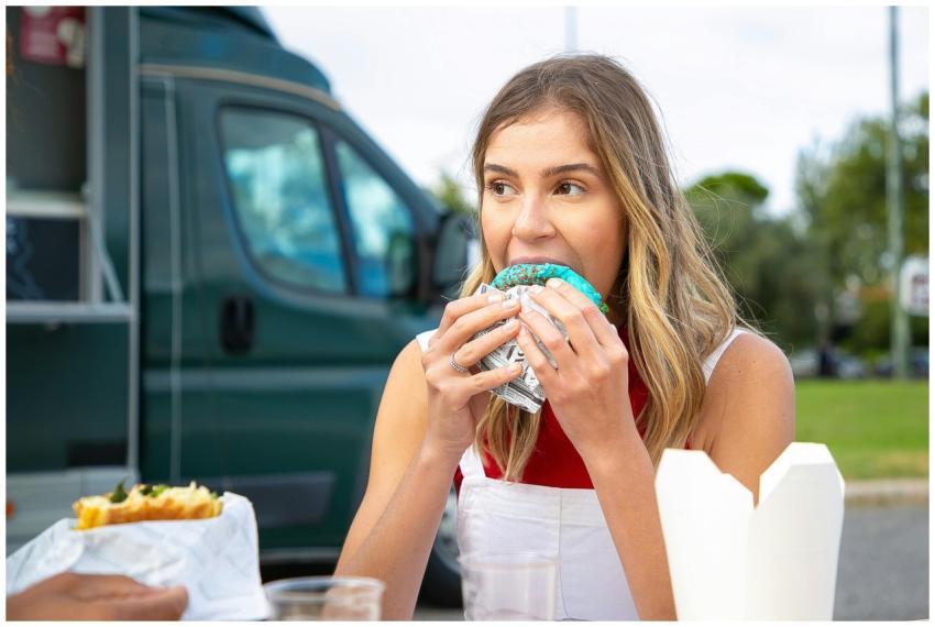 Young hungry female in casual clothes eating tasty
