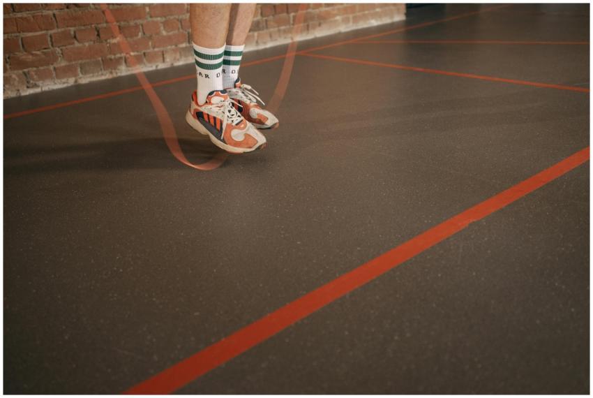 Feet of a person in sneakers skipping rope on an i