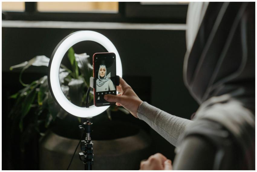 A woman in a hijab uses a smartphone and ring ligh