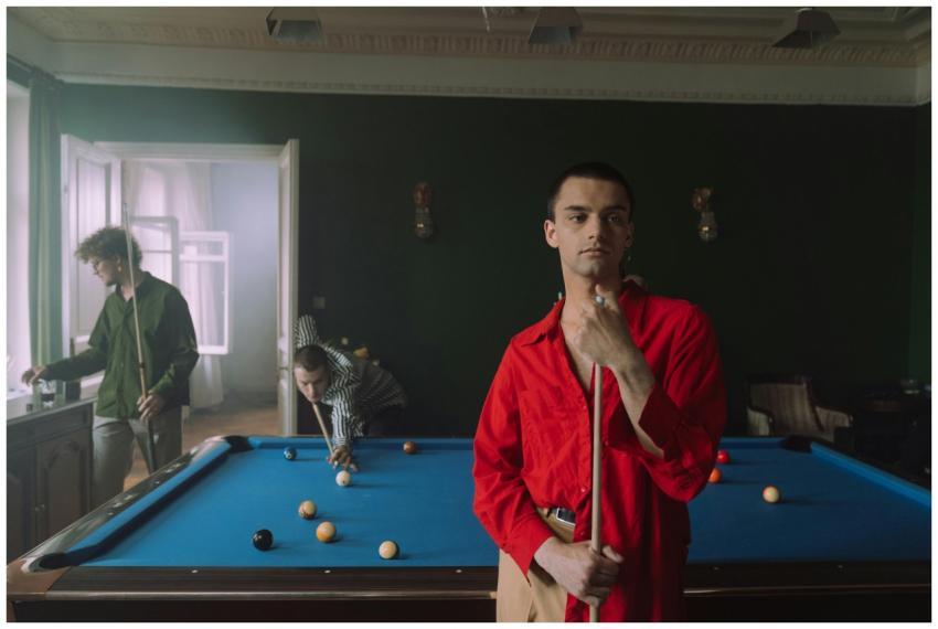 Three friends enjoy a game of billiards indoors, s