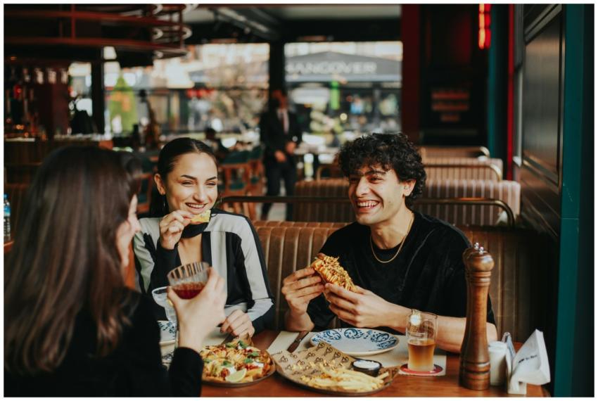 Group of friends laughing and eating at a restaura