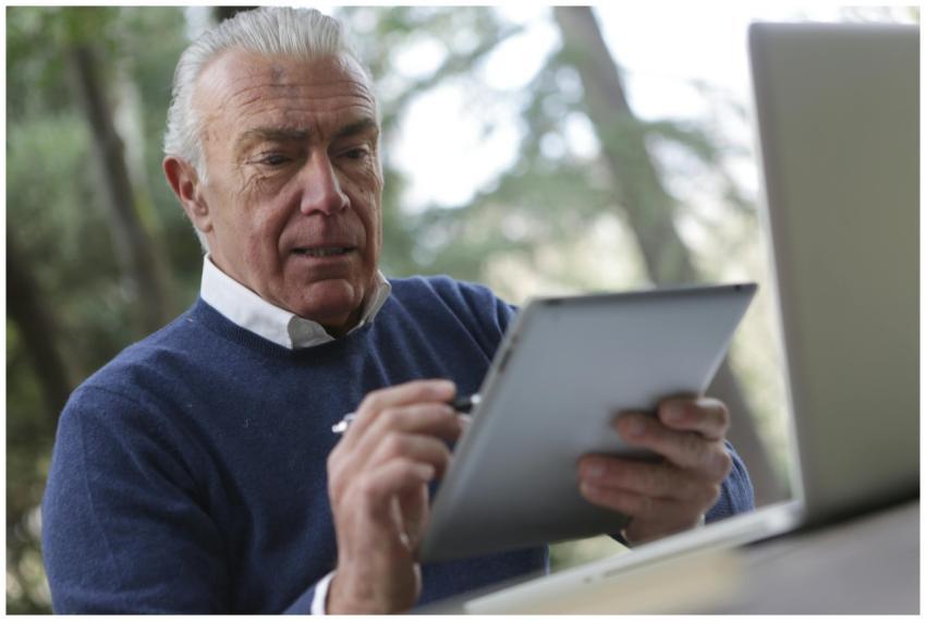 Elderly man focused on using a tablet in a natural