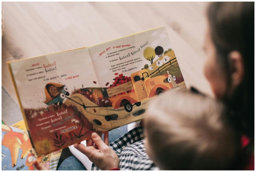 A mother and toddler sharing a story from an illus