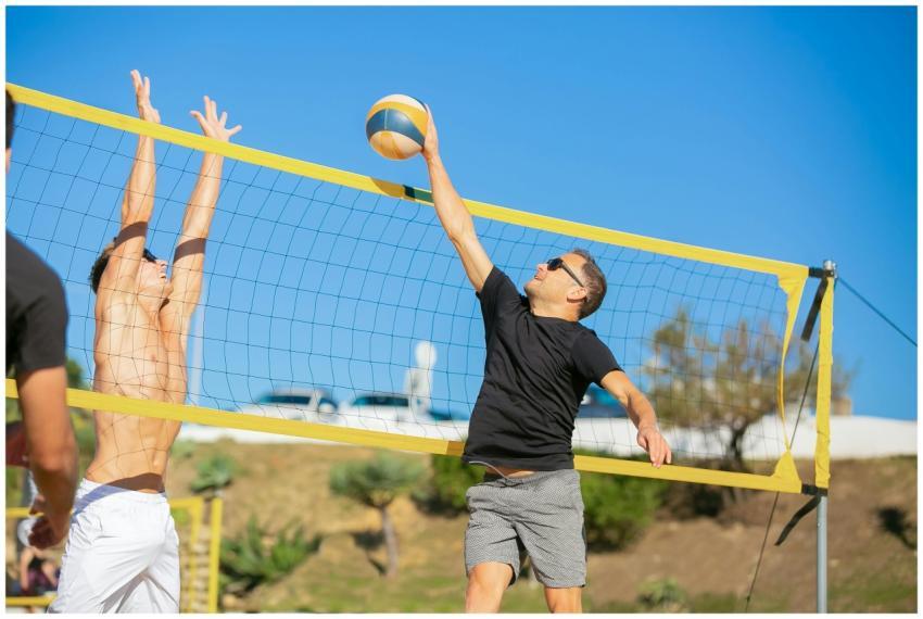 Two men competing in an intense beach volleyball g