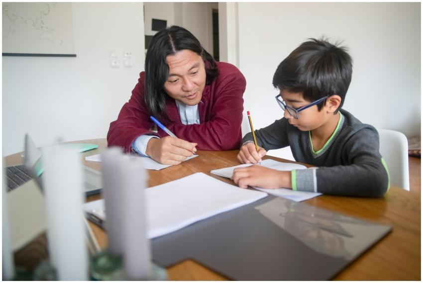 An adult tutoring a child at home, focusing on lea