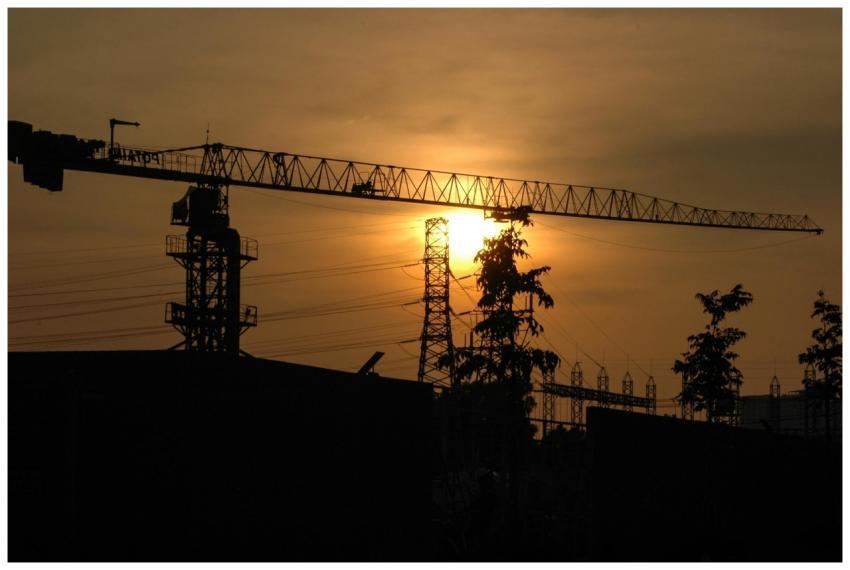 Silhouette of a construction crane with a sunset b