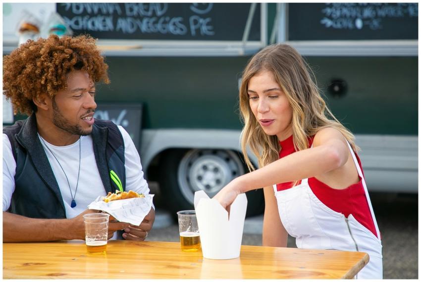 Positive young female eating french fries and drin