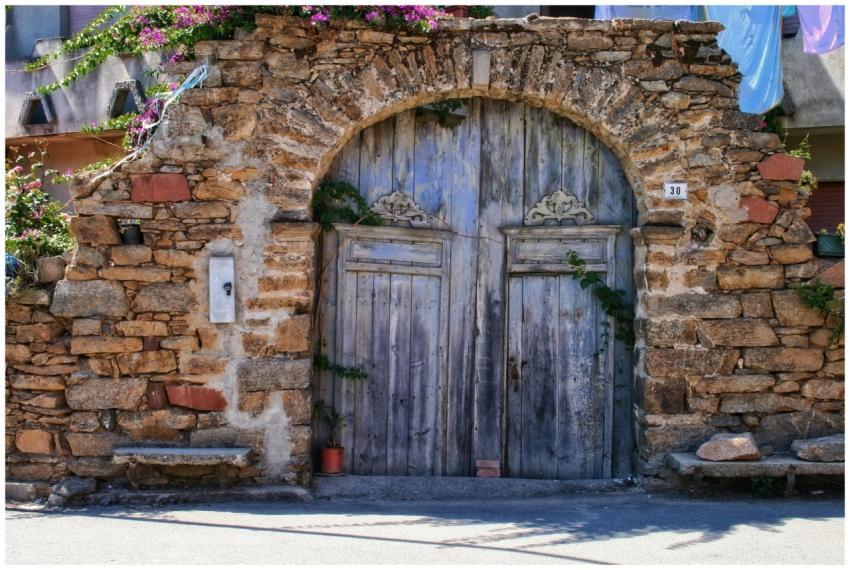 Historic stone archway with wooden doors in sunny