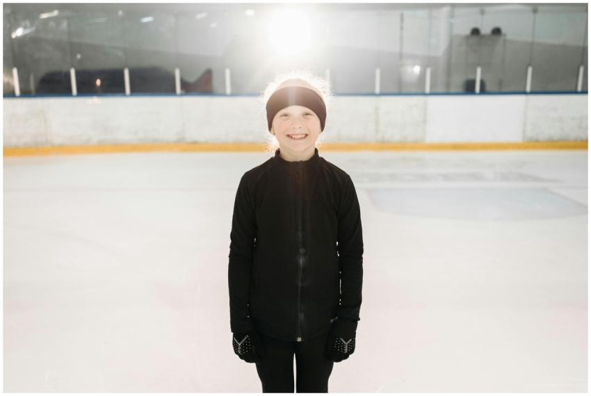 A young girl smiling on an indoor ice skating rink