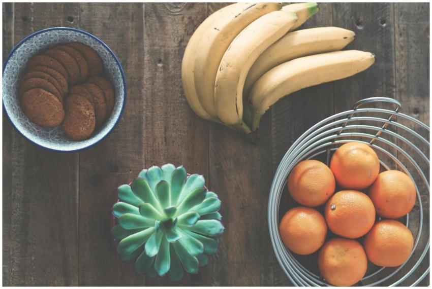 A rustic table setting featuring bananas, oranges,
