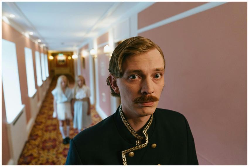 Concierge in ornate uniform stands in a luxurious