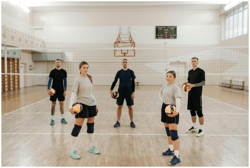A diverse volleyball team poses indoors with volle