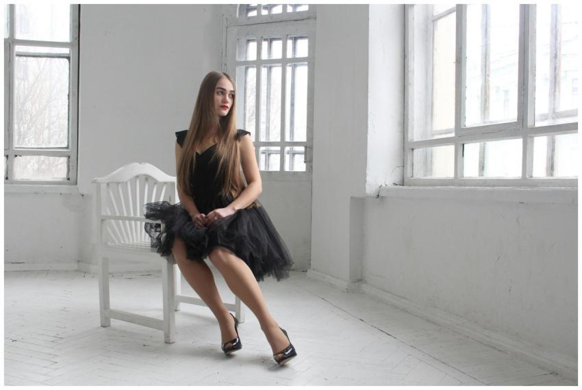 A young woman in an elegant black dress poses in a