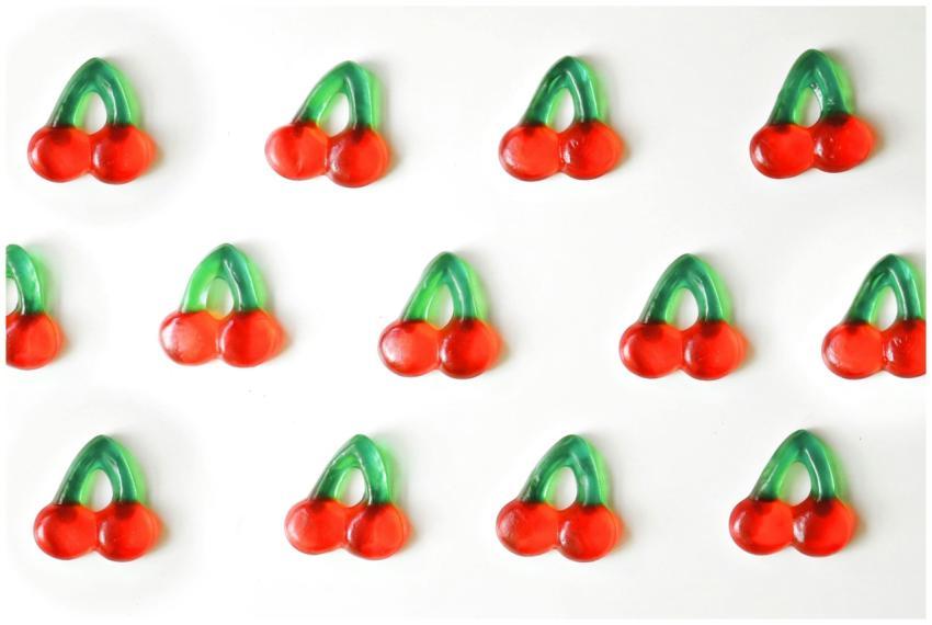 Rows of colorful cherry-shaped gummies on a bright