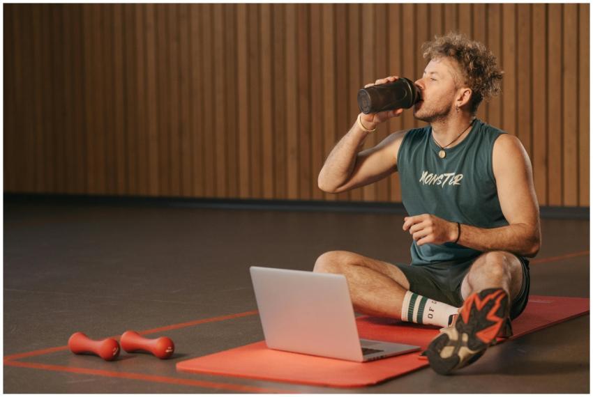 Man in gym drinking water during workout on exerci