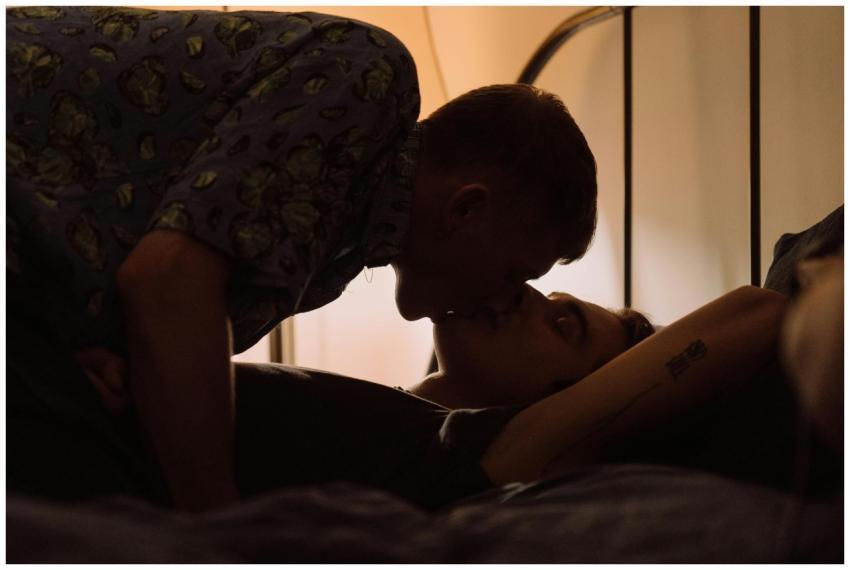A couple shares an intimate kiss in a softly lit b